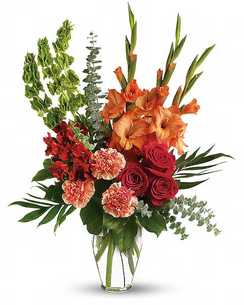 red, orange, and pink flowers in a clear vase