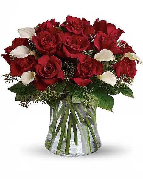 red roses and white calla lilies in a clear glass vase